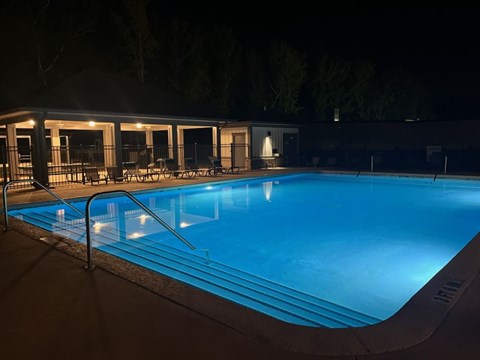 A swimming pool at night with lights on.