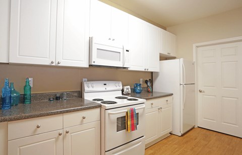 A kitchen with white cabinets and appliances.