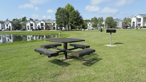 A picnic table sits in the middle of a grassy field.