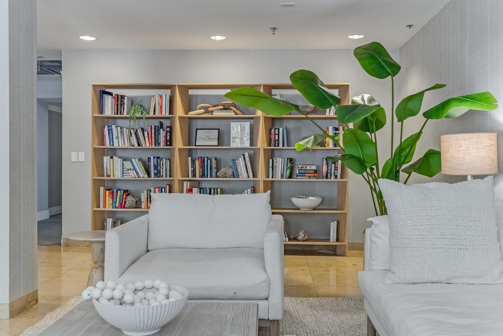 A living room with a white couch, a large bookshelf, and a large plant.