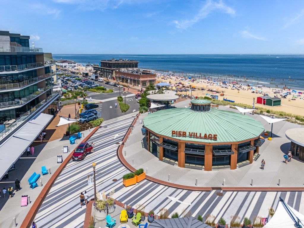 A view of a beachfront area with a large building that has the words "PIER VILLAGES" on it.