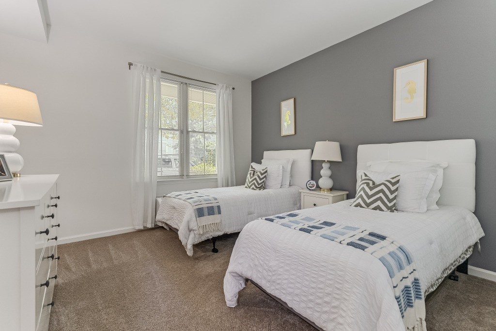 Two bedrooms with white beds and pillows.