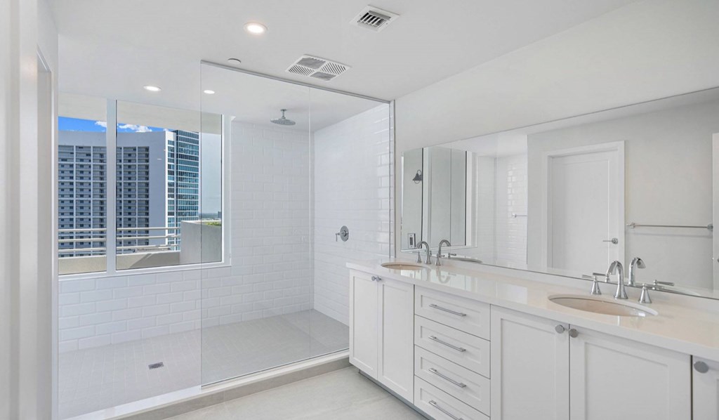 A white bathroom with a walk-in shower and double sinks.