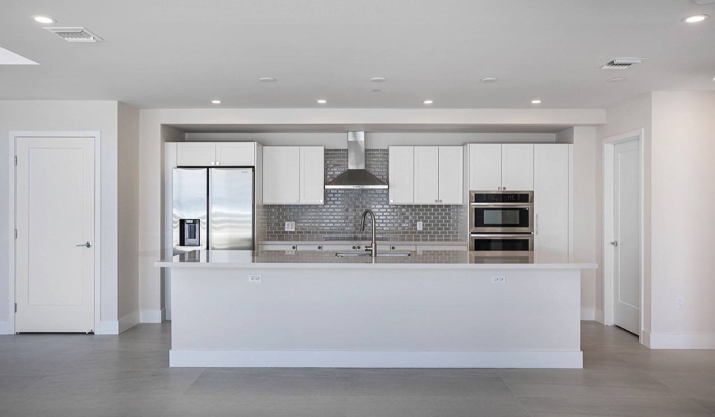 A modern kitchen with white cabinets and a large island.