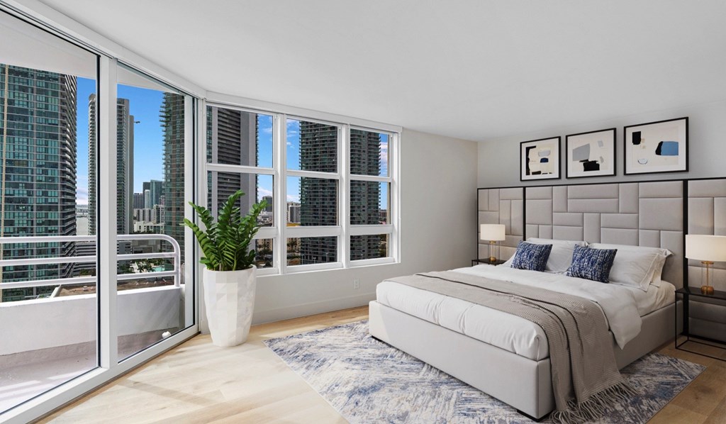 A bedroom with a large bed and a view of the city through the window.