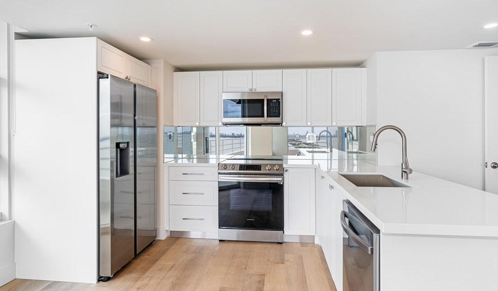 A modern kitchen with white cabinets and stainless steel appliances.