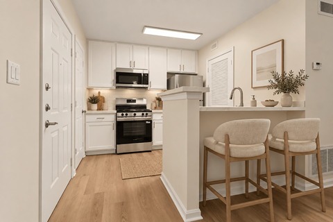 A kitchen with white cabinets and a white island with two chairs.