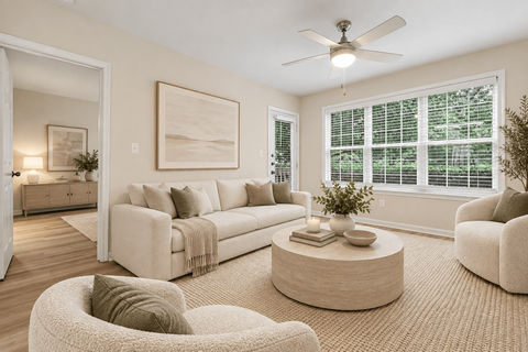 A living room with a white couch, a round coffee table, and a ceiling fan.