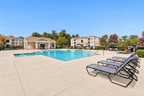 A pool with sun loungers and a building in the background.