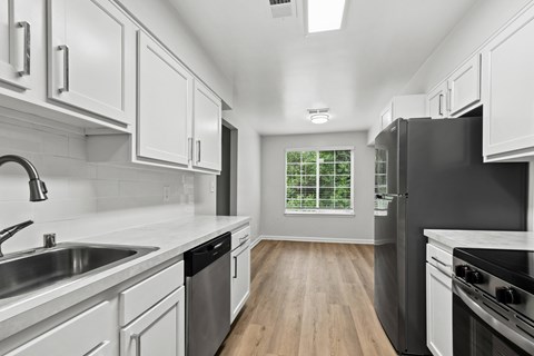 A modern kitchen with white cabinets and stainless steel appliances.