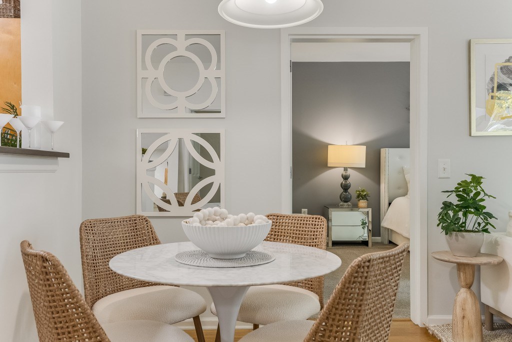 A white bowl is on a white table with four chairs around it.