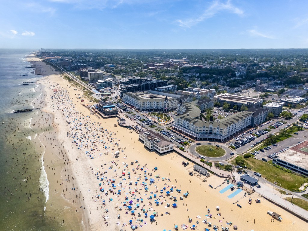 A crowded beach with people and umbrellas under a clear sky.