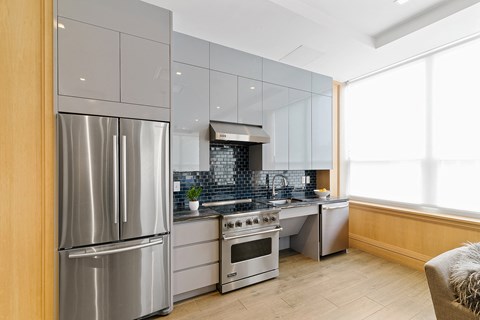 A modern kitchen with a stainless steel refrigerator and a stove top oven.