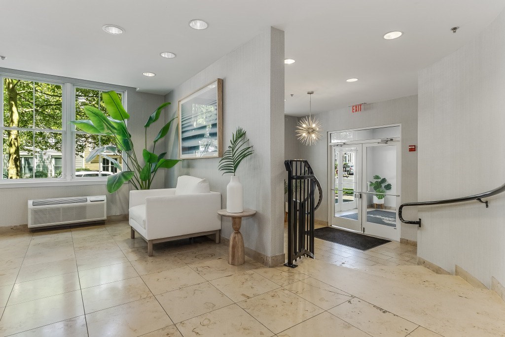 A white chair sits in a room with a large window and a plant.
