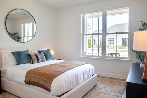 A bedroom with a large bed and a round mirror on the wall.