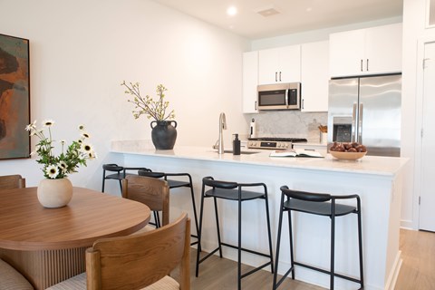 A kitchen with a table and chairs in front of it.