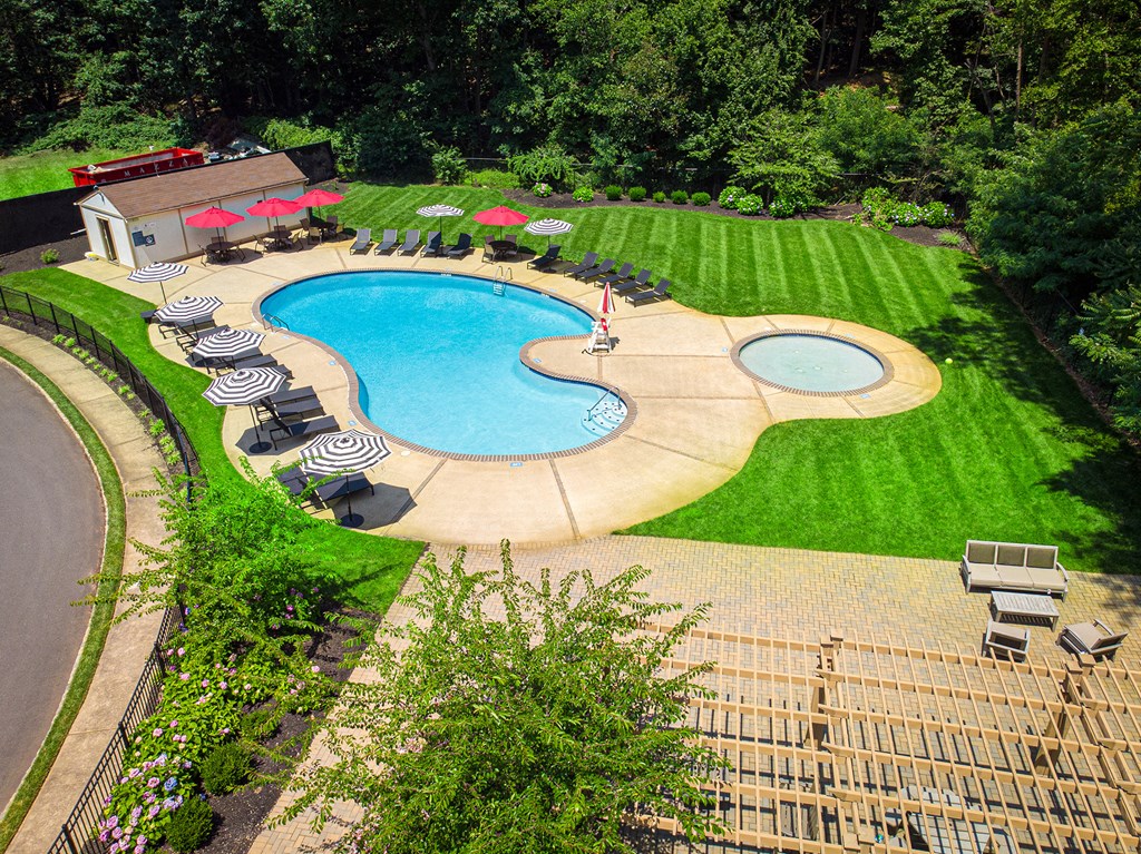 A large outdoor swimming pool surrounded by a grassy area and trees at Atlantic Pointe Apartments, Atlantic Highlands, 07716 