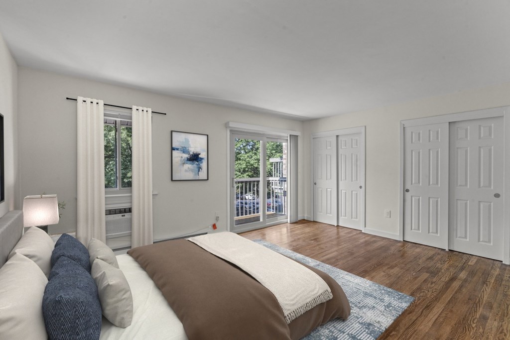 A bedroom with a large bed and a view of a balcony at Atlantic Pointe Apartments, Atlantic Highlands New Jersey