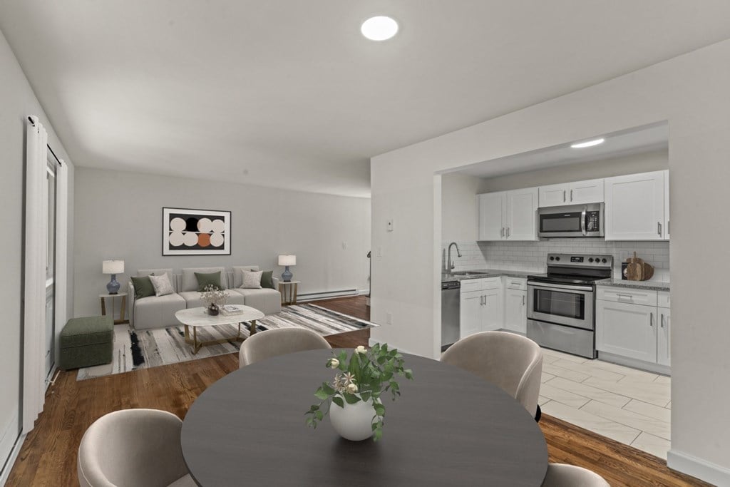 A modern kitchen with a dining table and chairs in the foreground at Atlantic Pointe Apartments, New Jersey, 07716