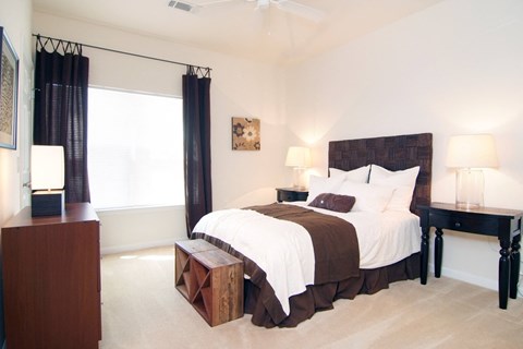 A bedroom with a large bed and a wooden nightstand.