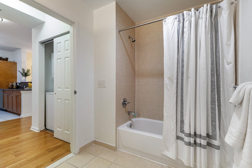 a bathroom with a shower and a tub and a door to a closet at Pier Village Apartments, Long Branch, NJ