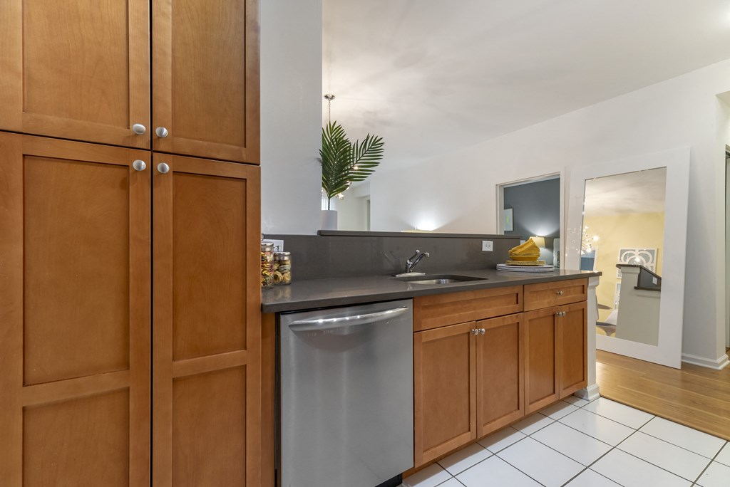 a kitchen with a stainless steel dishwasher and wooden cabinets