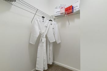 spacious closet with white robes and hangers in a studio apartment