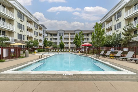 Outdoor swimming pool with lounge seating and umbrellas at Pier Village Apartments, Long Branch, 7740