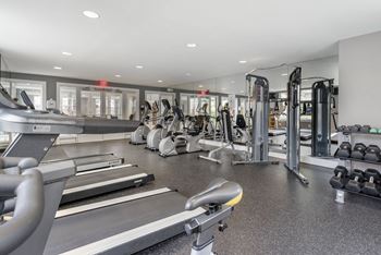 a gym with cardio equipment and weights in a building with windows