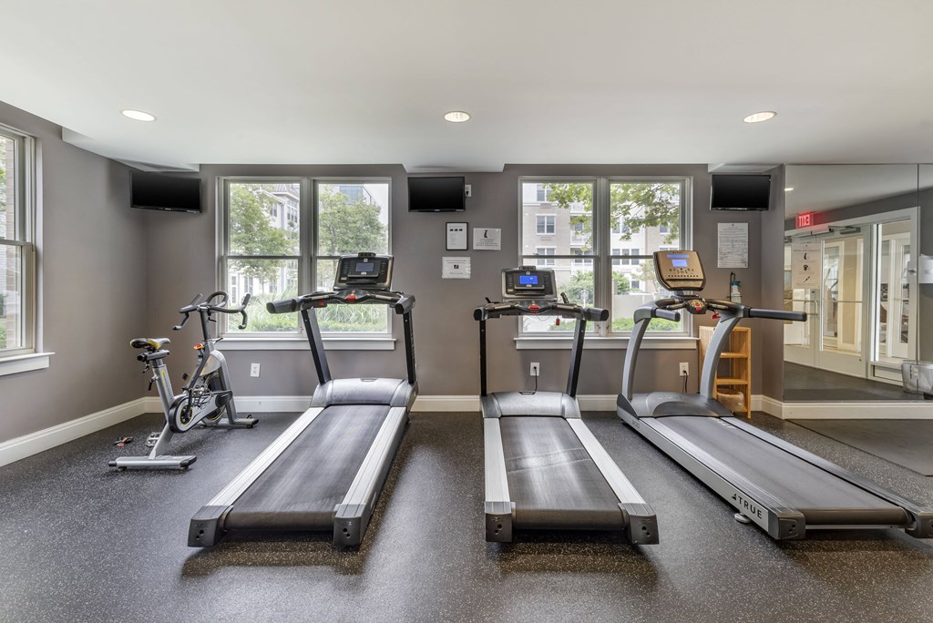 two treadmills and two bikes in a gym with windows at Pier Village Apartments, New Jersey, 07740