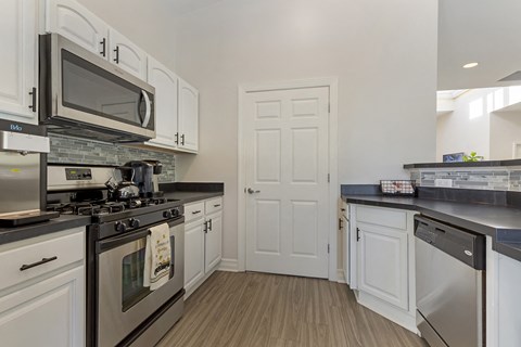 A kitchen with white cabinets and black countertops.