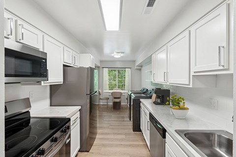 A modern kitchen with white cabinets and stainless steel appliances.