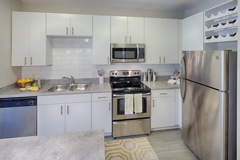 a modern kitchen with stainless steel appliances and white cabinets