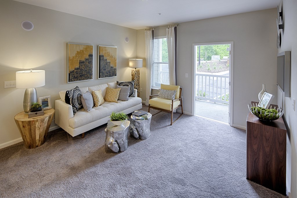 A living room with a couch, two chairs, and a table with a vase on it at Capital Creek at Heritage Apartments, Wake Forest