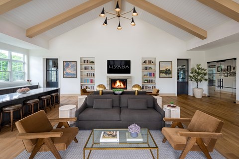 A living room with a grey couch and wooden chairs.