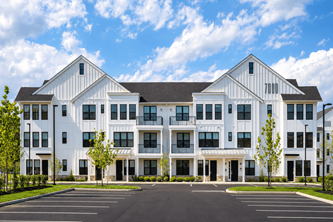 A large white building with a black roof and a parking lot in front.