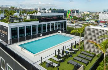 an overhead view of a hotel pool with lounge chairs and a city in the background