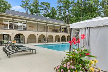A pool area with sun loungers and a building in the background.
