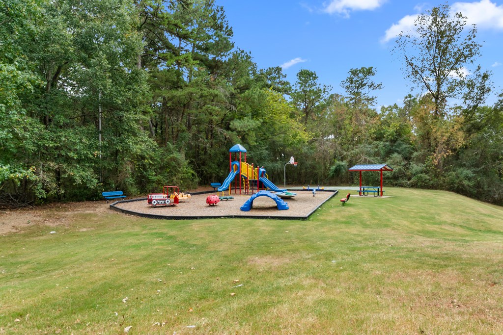 A playground with a blue and yellow slide and a red swing set.