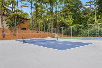 A tennis court surrounded by a fence and trees.