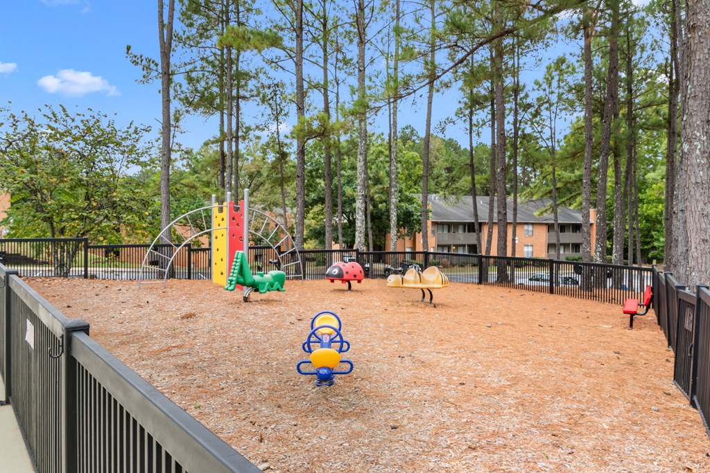 A playground with a black fence and a red slide.