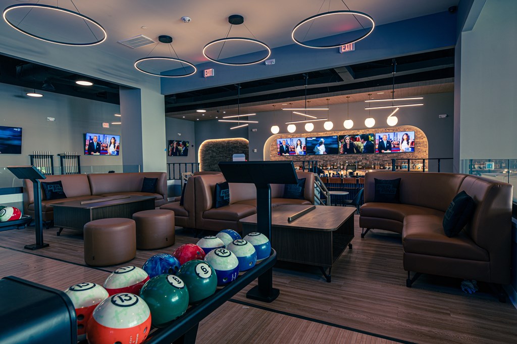 A bowling alley with a row of balls and chairs.