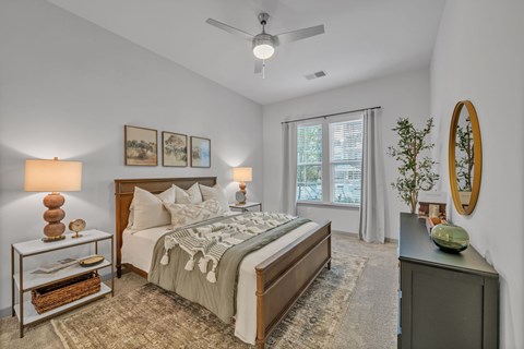 A bedroom with a bed, nightstand, and a ceiling fan.