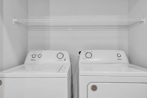 Two white front loading washing machines in a laundry room.
