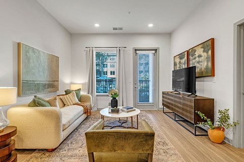 A living room with a couch, a chair, a coffee table, and a television.