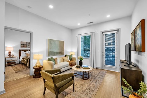 A well-lit living room with a couch, chair, and a painting on the wall.