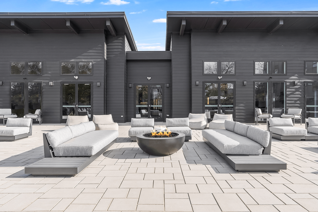 A modern outdoor seating area with a fire pit in the center.