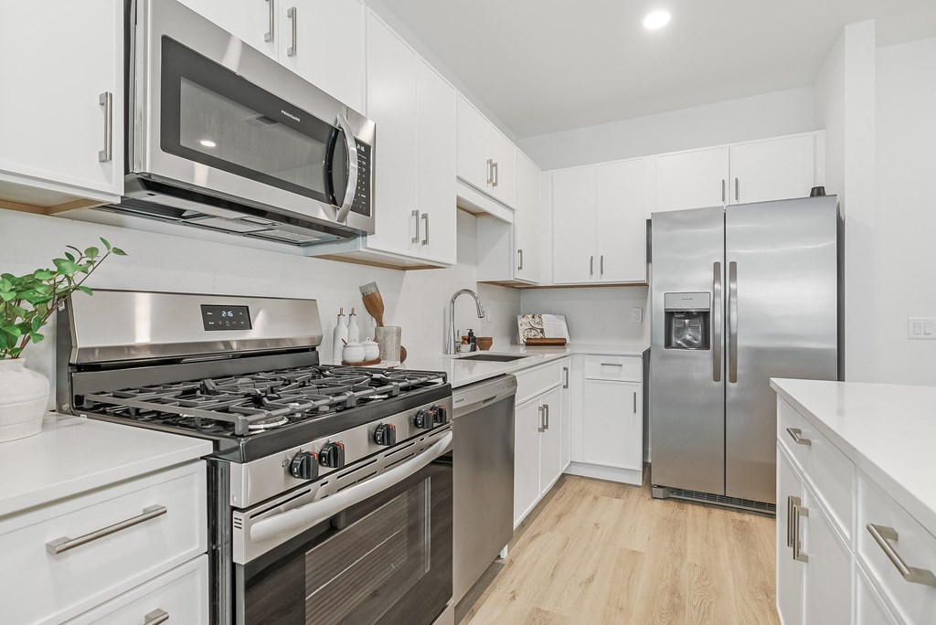 a white kitchen with stainless steel appliances and white cabinets