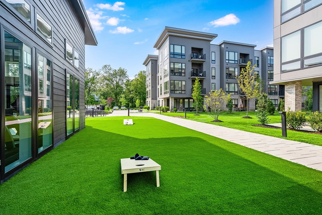 A white table with a black bag on it sits on a green lawn in front of apartment buildings.