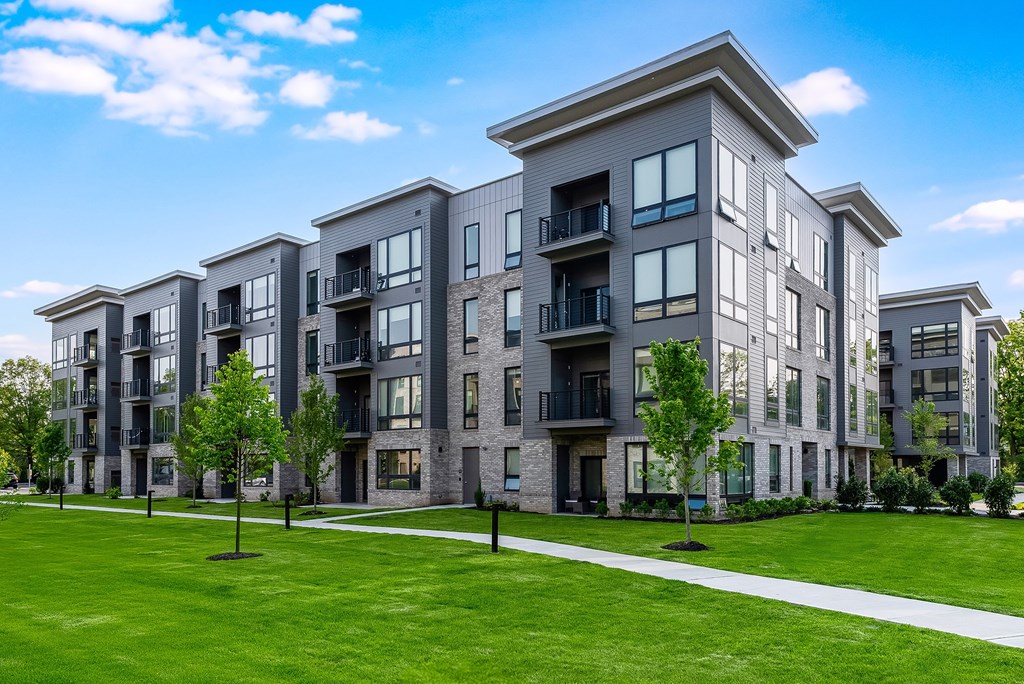 A modern apartment building with a well-maintained lawn in front.